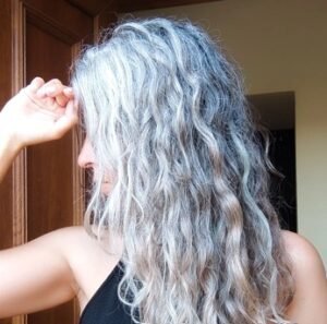 mujer con el pelo largo con canas rizado